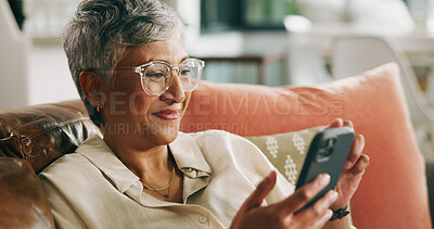 Buy stock photo Mature woman, phone and smile on couch with contact, texting and notification on web in home. Person, smartphone and happy with mobile app, post and relax with social network in lounge at apartment