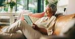 Mature woman, relax and tablet on sofa in home, smile and reading ebook on web in living room. Person, happy and tech with video, movie and film with streaming subscription on couch at apartment