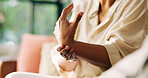 Hands, arthritis and person with wrist pain on sofa for joint injury, inflammation and tension. Carpal tunnel, woman and sprain in home for osteoporosis and muscle fatigue from fibromyalgia disease
