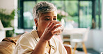 Mature woman, drinking water and home on sofa, relax or hydration for wellness in living room. Person, glass and thirsty with liquid for nutrition, detox or gut health on couch in lounge at apartment