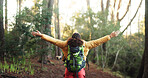 Woman, open arms and back with success for hiking, achievement and goals on adventure in forest. Person, celebration and bag with cheers in woods with winning, target and freedom on trail in Nigeria