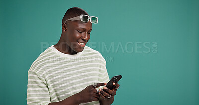 Buy stock photo Phone, smile and black man in studio for social media, text message or reading fashion blog. Mobile, online chat and happy model on digital app for news, check forum and space at green background