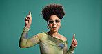 Dancing, pointing and happy woman in studio with fashion, energy and moves for celebration. African person, excited and gesture for groove, sunglasses or good mood on green background with space