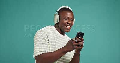 Buy stock photo Headphones, smile and black man in studio, cellphone or listening to music on green background. African person, space or mobile user with headset, audio or smartphone with sound, digital app or radio