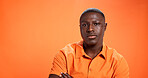 Serious, fashion model and man with pride, studio or arms crossed with cool outfit and mockup space. Orange background, black person and attitude for stylish clothing, portrait and designer shirt