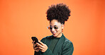 Woman, phone and texting in studio with smile, chat and reading post on mobile app on orange background. Happy person, smartphone and notification with contact, scroll and choice on social network