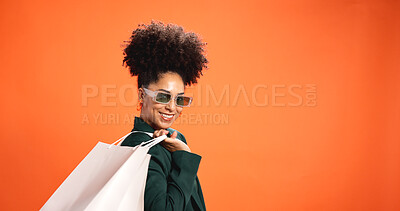 Buy stock photo Fashion, shopper and woman with shopping bags, studio or trendy with sunglasses or orange background. Happy, customer and African person with discount for purchase, mockup space and style with shades