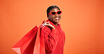 Space, shopping bag or happy black woman in studio for fashion choice and financial freedom. Mockup, customer or cool African person on orange background for clothes sale, discount deal or bargain