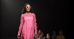 Woman, model and walking on catwalk with fashion, confidence or showcase with audience. Style, sunglasses and person at black background space with designer clothing, brand ambassador or runway event