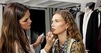 Woman, model and backstage with makeup artist, lipstick application and makeover process. People, cosmetics and getting ready for photoshoot, beauty touch up and preparation for production in studio