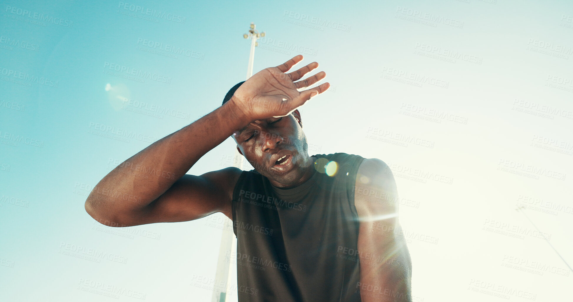 Buy stock photo Fatigue, fitness and black man by blue sky for running, workout or training for marathon with break. Tired, sweating and African male athlete with rest for outdoor cardio exercise from below.