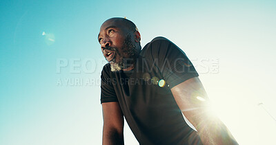 Buy stock photo Breathing, fitness and black man by blue sky for running, workout or training for marathon with break. Fatigue, lens flare and African mature athlete with rest for outdoor cardio exercise from below.