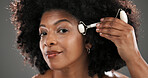 Woman, jade roller and cosmetics in studio for facial routine, stone or anti aging by background. African person, beauty and portrait for massage tools, circulation or skincare for results in Kenya