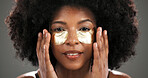 Skincare, eye mask and portrait of black woman in studio for facial treatment, beauty and dark circles. Dermatology, salon and person with pads for anti aging, health and cosmetics on gray background
