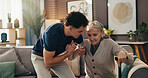 Senior woman, caregiver and help with walking stick on sofa for mobility, assistance and recovery. Health worker, elderly person and support with cane in assisted living for balance or rehabilitation