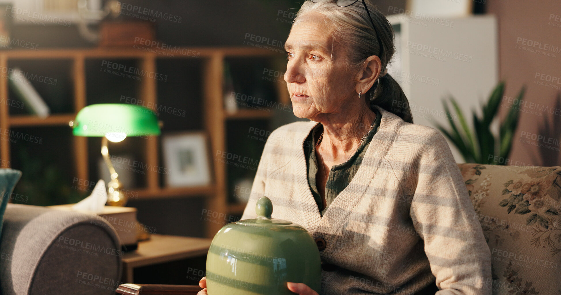 Buy stock photo Sad, old woman and thinking with urn in home for mourning, grief and loneliness in retirement. Loss, sorrow and senior person with depression in lounge for memory, bereavement and reflection of death