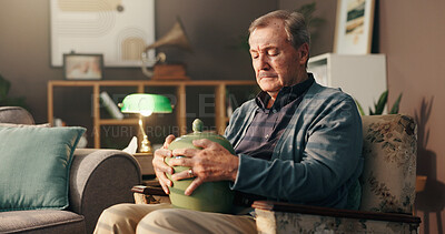Buy stock photo Senior, sad man and home with urn or memory for grief, loss or mourning in thought on chair. Elderly, male person or widower thinking with vase of ashes for nostalgia, missing piece or lonely house