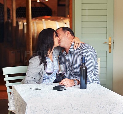 Buy stock photo Love, kiss and a couple on a wine farm together in celebration of love or their anniversary. Kissing, romance or dating with a loving man and woman at a table in a winery feeling happy while bonding