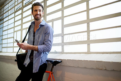Buy stock photo Designer, ideas and happy man with phone for thinking, decision and social media in creative startup. Smile, window and entrepreneur with bicycle on mobile for internet, research and article blog