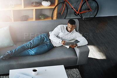 Buy stock photo Man, relax and tablet in home on sofa, networking and social media for online streaming in living room. Happy, research and technology on website, elearning and reading internet blog in apartment