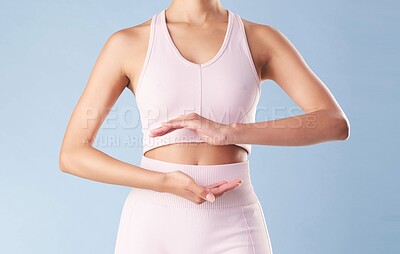 Buy stock photo Studio, woman or hands on stomach for fitness, health or diet with wellness after workout. Blue background, female person or model with abdomen frame for gut digestion, body transformation or closeup
