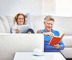 Mature man reading a book and mature woman browsing online on a digital tablet while relaxing together at home