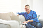 Mature man browsing online on a laptop while relaxing alone on a sofa at home