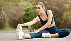 One fit young mixed race woman touching her feet and stretching legs for warmup to prevent injury while exercising outdoors. Female athlete preparing body and muscles for training workout or run at the park