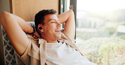 Buy stock photo Man, earphones and relax by window in home with smile, memory and reflection with music in morning. Person, ear pods and happy with audio streaming, subscription and thinking on couch at apartment