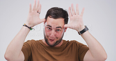 Buy stock photo Silly man, portrait and funny face with hands in studio for antlers or ears on a white background. Male person, goofy and model with playful attitude, comic or behaviour for joke, humor or comedy