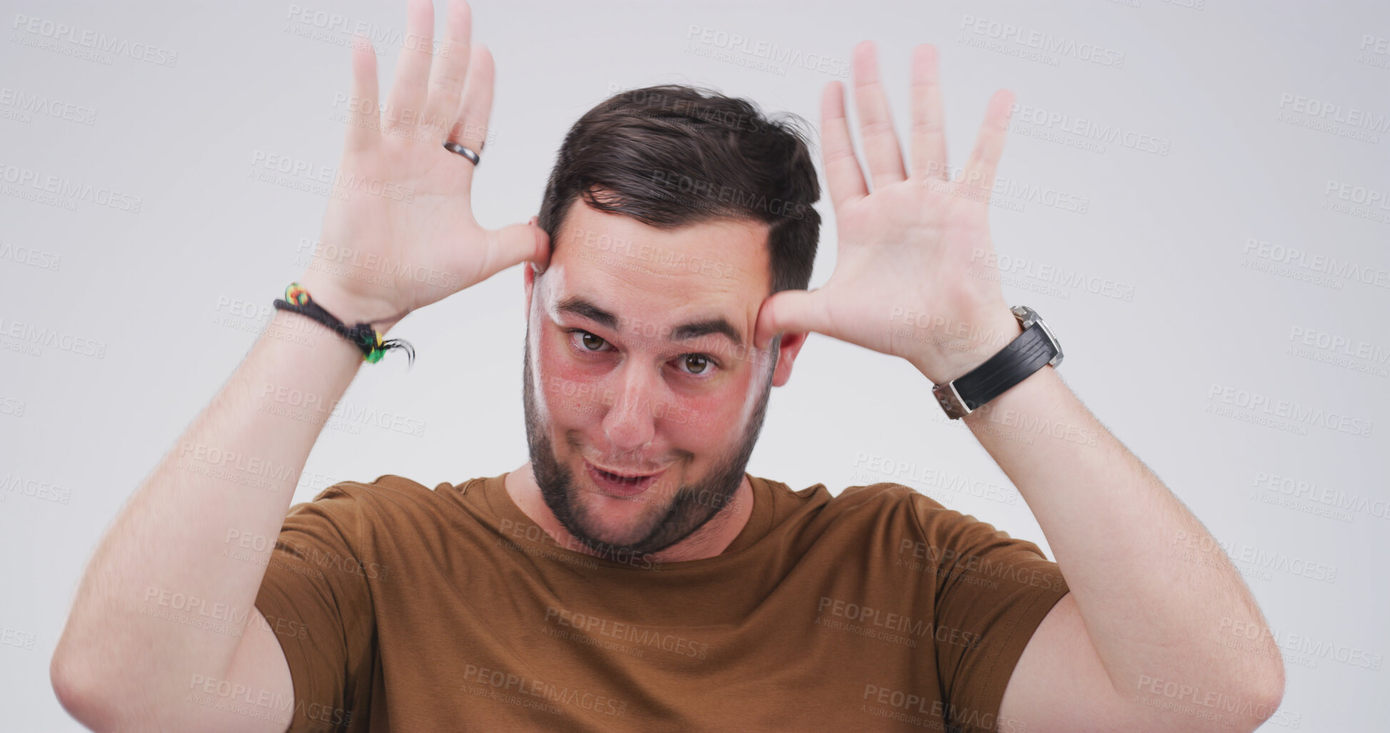 Buy stock photo Silly man, portrait and funny face with hands in studio for antlers or ears on a white background. Male person, goofy and model with playful attitude, comic or behaviour for joke, humor or comedy