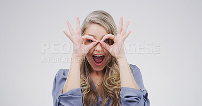 Buy stock photo Binocular, hands and silly woman with playful expression or gesture in studio for vision or funny face. Happy female person, comic finger glasses and white background for joke, excited or perspective