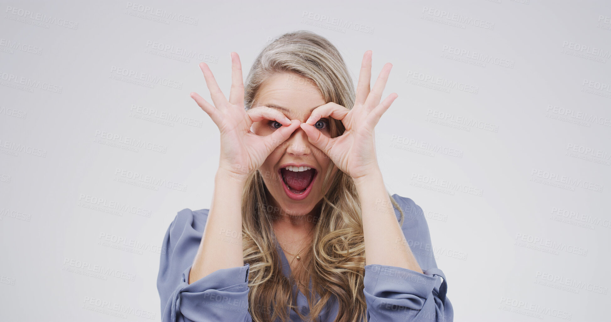 Buy stock photo Binocular, hands and silly woman with playful expression or gesture in studio for vision or funny face. Happy female person, comic finger glasses and white background for joke, excited or perspective