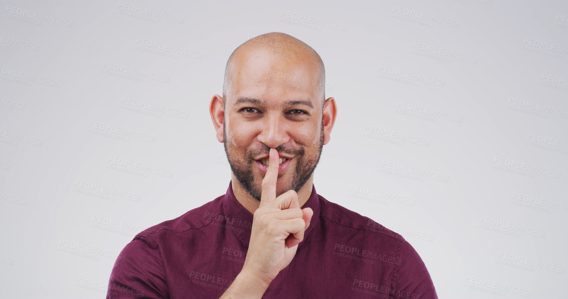 Buy stock photo Portrait, man and finger on lips in studio for secret, quiet or privacy gesture for gossip. Happy, confidential and person from Colombia with silent hand sign for rumor or mystery by white background