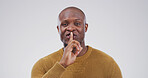 Portrait, black man and finger on lips in studio for secret, quiet or privacy gesture for gossip. Happy, confidential and African person with silent hand sign for rumor or mystery by white background