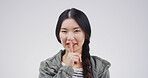 Happy, portrait and woman in studio with secret, gossip or confidential hand gesture for privacy. Quiet, smile and Asian person with finger on lips for silence or noise control by white background.