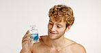Studio, smile and man with perfume for fragrance, grooming or hygiene on white background. Cologne, fresh scent or happy model with cosmetics product for self care, beauty or mask odor to smell clean