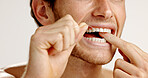 Dental hygiene, floss and man in studio with wellness, health and mouth routine in morning. Oral care, fresh breath and person with string for cleaning teeth with plaque removal by white background.