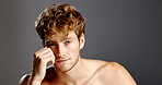 Man, beauty and hair in portrait with skincare, beard and dermatology on a grey background. Shirtless, self care and serious male model with cosmetics, confidence and grooming with hand on face