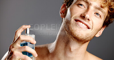 Buy stock photo Cologne, face and smile of man in studio with spray bottle for aroma, fragrance or fresh smell. Perfume, product and satisfaction with happy person on gray background for essence scent in glass