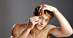 Skincare, eyebrows and tweezers with face of model for grooming, hygiene or hair removal in studio. Cosmetic, treatment and facial growth with man, beauty tool and morning routine on gray background