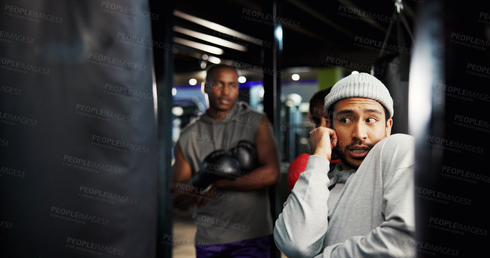 Buy stock photo Boxing, coach or teach defense in gym with position, group session or training at punching bag. Man, fitness or athletes in sport center for instruction, combat technique or learning to deflect