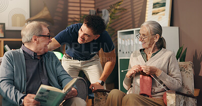 Buy stock photo Living room, caregiver and talk with old couple, hobby and senior people with smile in nursing home. Knitting, elderly woman and man with book in lounge, nurse and conversation with patient in house