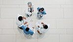 Doctor, medical team and meeting with documents above for healthcare development or mission. Top view, group or health employees with paperwork in huddle for progress or performance at hospital