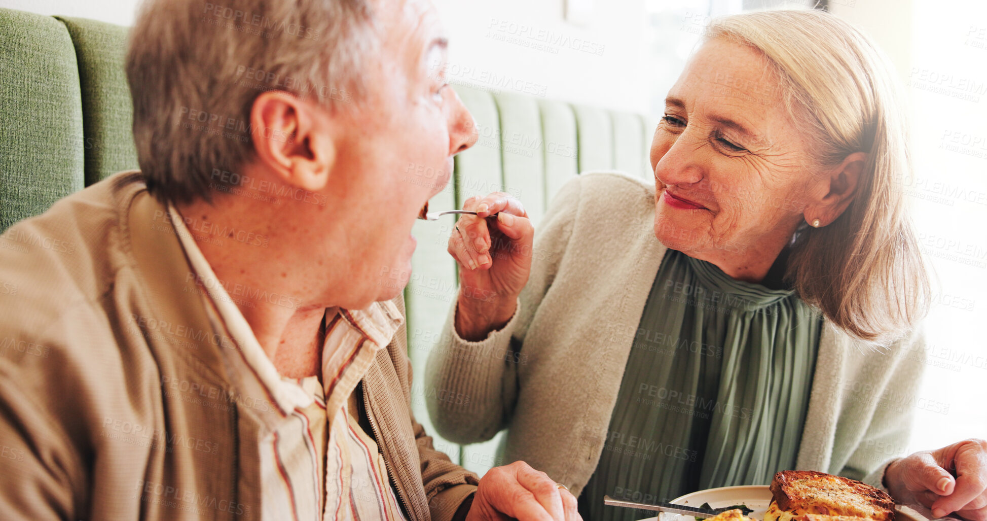 Buy stock photo Eating, feed or senior couple in cafe on date together in retirement for love, breakfast or food. Share, taste or elderly people in restaurant with lunch and laugh at diner for romantic anniversary