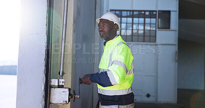 Buy stock photo Mature man, garage door and open for shipping, stock or storage at warehouse for supply chain. African person, engineer and maintenance for gate, check or commercial distribution at industrial plant