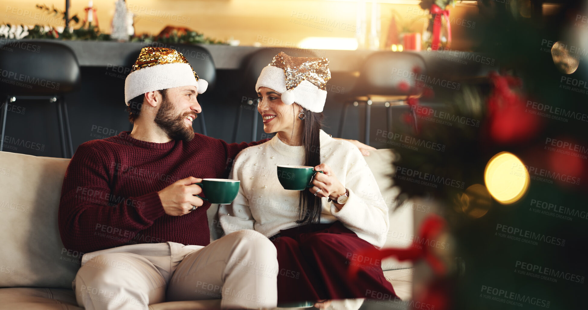 Buy stock photo Christmas, happy and couple with coffee in home for festive morning with santa hat for celebration. Smile, love and man with woman on sofa for relax, bonding and drinking eggnog for xmas together.