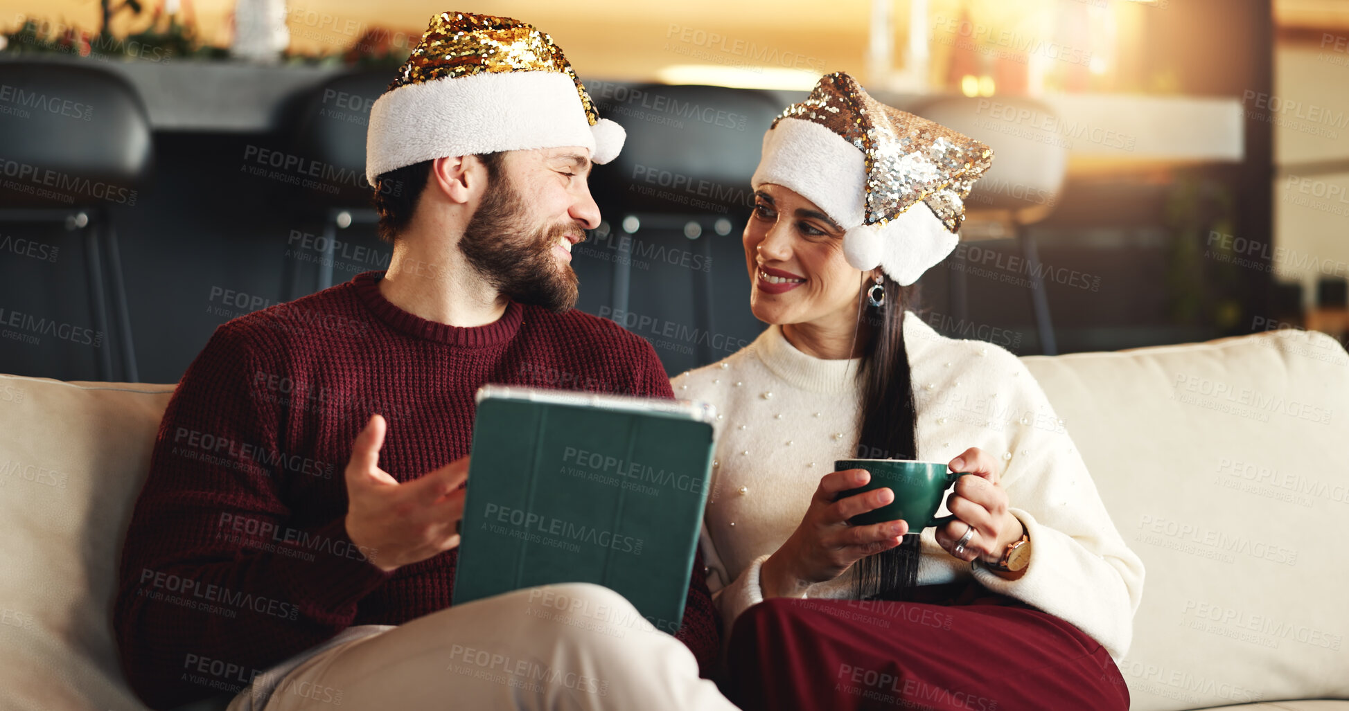 Buy stock photo Christmas, coffee and couple on sofa, tablet or bonding together with conversation, social media or app. Home, Xmas or man on couch, woman or eggnog with online entertainment, love or holiday season