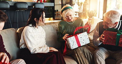 Buy stock photo Christmas, gift and old woman with family on sofa for holiday season, bonding and support. Festive celebration, smile and xmas present with people in living room of home for love, package and relax