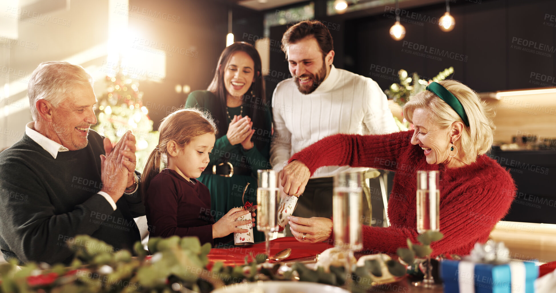 Buy stock photo Celebration, Christmas cracker and girl with big family for for vacation, bonding and excited. December, holiday or festive surprise with parents, grandparents and child with social gathering in home